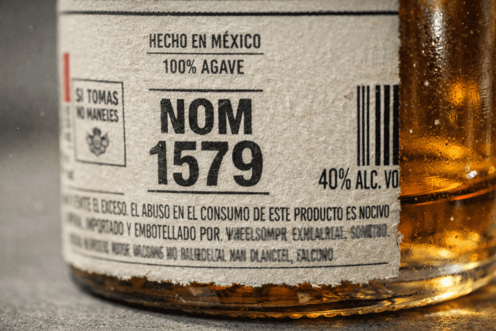Close-up of tequila bottle back label showing NOM number regulatory code for distillery identification